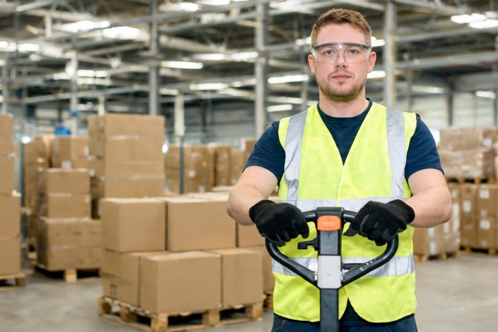 Warehouse worker wearing supplied protective equipment while operating equipment