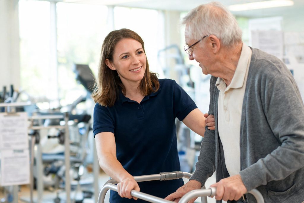 Physiotherapist supporting a patient walking with a frame