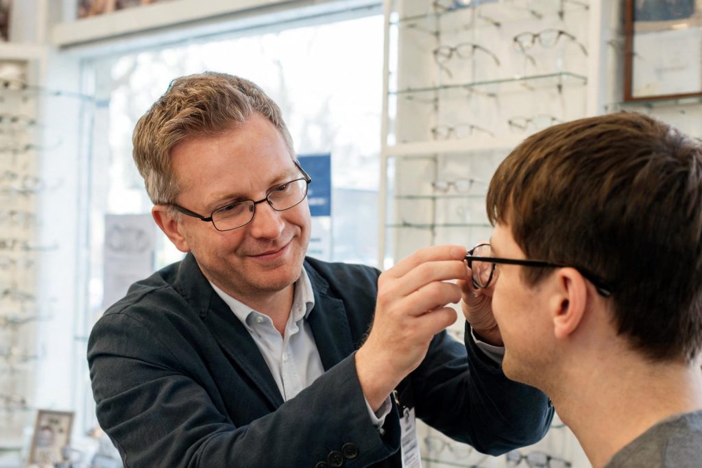 Dispensing optician fitting a pair of glasses for a customer